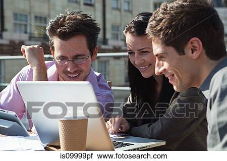 Three people looking at a laptop View Large Photo Image Stock Image - Three people looking at a laptop. Fotosearch