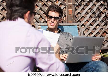 Two men having an informal meeting in a garden View Large Photo Image Stock Photograph - Two men having an informal meeting in a garden. Fotosearch