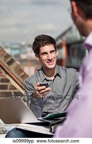 Stock Photography - Two men in a meeting in a roof garden. Fotosearch