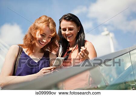 Stock Photo - Two young women using a smart phone. Fotosearch
