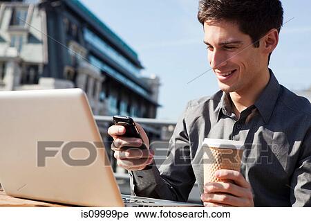 Young man working outside using his laptop and phone View Large Photo Image Stock Image - Young man working outside using his laptop and phone. Fotosearch