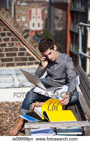 Picture - Young man working with a laptop on a rooftop. Fotosearch
