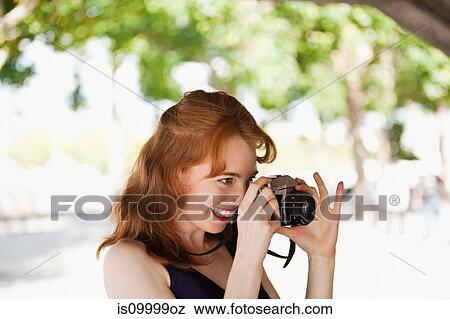 Young woman taking a photograph outside View Large Photo Image Stock Photo - Young woman taking a photograph outside. Fotosearch