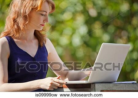 Stock Photo - Young woman using a laptop outside. Fotosearch