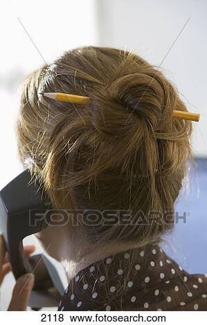 Businesswoman Using Telephone Pencil Threaded Through Ginger Hair