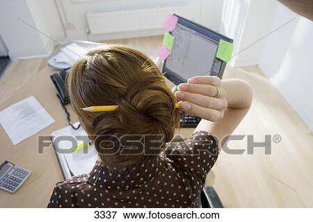 Businesswoman Working In Office Holding Pencil Threaded Through