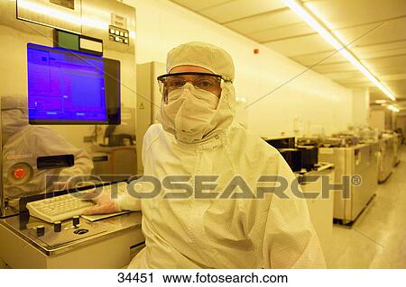 Portrait Of Scientist In Clean Suit Working At Computer In Silicon Wafer Manufacturing Clean Room Stock Image