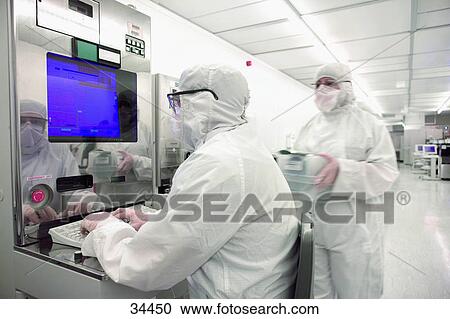 Scientist In Clean Suit Working At Computer In Silicon Wafer Manufacturing Clean Room Stock Image