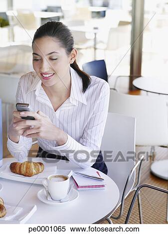 Stock Image - Woman in a cafÈ texting on her mobile phone. Fotosearch - Search Stock Photos, Mural Pictures, Photographs, and Photo Clipart