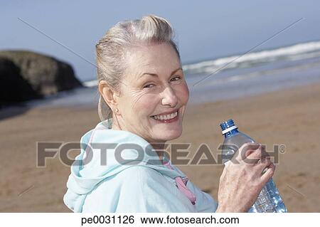 senior woman drinking water at the beach View Large Photo Image Stock Image - senior woman drinking water at the beach. Fotosearch - Search Stock Photography, Poster Photos, Pictures, and Photo Clip Art