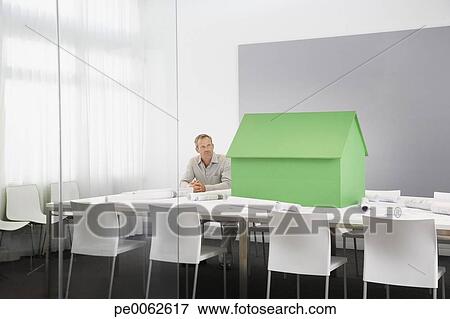 Businessman with small model house on conference table View Large Photo Image Picture - Businessman with small model house on conference table. Fotosearch - Search Stock Photography, Photos, Prints, Images, and Photo Clipart