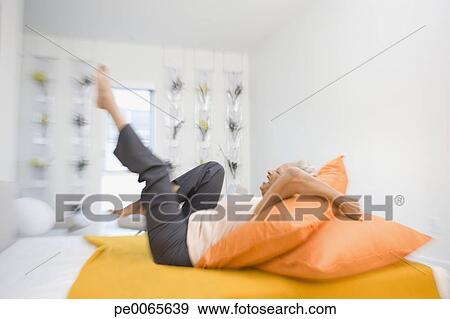 Stock Photograph - Senior woman celebrating on bed. Fotosearch - Search Stock Photography, Posters, Pictures, and Photo Clipart Images