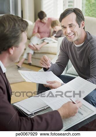 Stock Photograph - Man meeting with financial advisor in living room. Fotosearch - Search Stock Photography, Posters, Pictures, and Photo Clipart Images