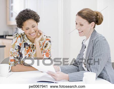 Stock Photography - Woman reviewing paperwork with financial advisor. Fotosearch - Search Stock Photos, Pictures, Prints, Images, and Photo Clip Art