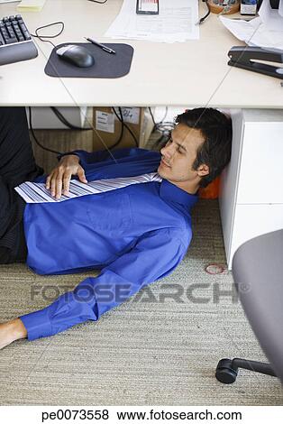 Businessman Sleeping Under Desk In Office Stock Photo Pe0073558