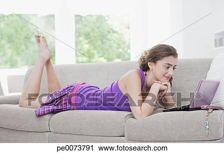 Teenage Girl Laying On Sofa And Using Laptop Stock Image