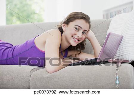 Teenage Girl Laying On Sofa And Using Laptop Stock Image