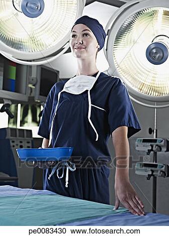 Stock Photography - Portrait of confident nurse holding kidney dish under surgical lights. Fotosearch - Search Stock Photos, Pictures, Wall Murals, Images, and Photo Clipart