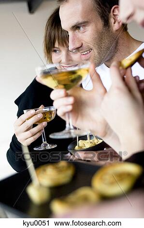 Stock Image - 2 women and a man holding glass of champagne. Fotosearch