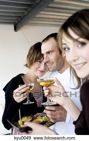 2 women and a man holding glasses of champagne View Large Photo Image Stock Photo - 2 women and a man holding glasses of champagne. Fotosearch
