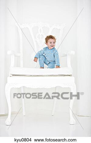 Baby boy sitting in an armchair and smiling View Large Photo Image Picture - Baby boy sitting in an armchair and smiling. Fotosearch
