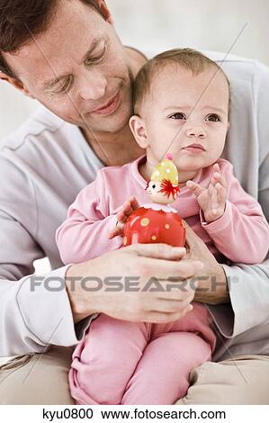 Stock Image - Baby girl sitting on her father's lap. Fotosearch