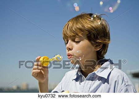 Boy blowing bubbles with a bubble wand View Large Photo Image Stock Image - Boy blowing bubbles with a bubble wand. Fotosearch