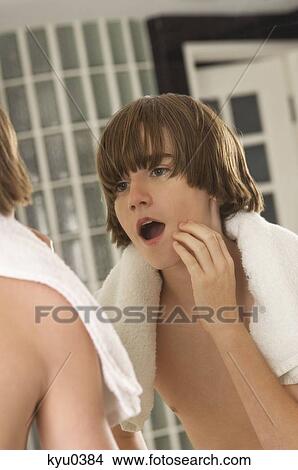 Boy examining his face in the bathroom mirror View Large Photo Image Picture - Boy examining his face in the bathroom mirror. Fotosearch