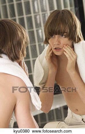 Boy examining his face in the bathroom mirror View Large Photo Image Stock Image - Boy examining his face in the bathroom mirror. Fotosearch