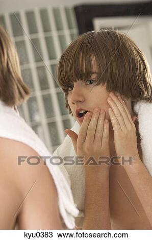 Boy examining his face in the bathroom mirror View Large Photo Image Stock Image - Boy examining his face in the bathroom mirror. Fotosearch