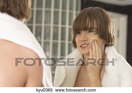 Boy examining his face in the bathroom mirror View Large Photo Image Stock Photography - Boy examining his face in the bathroom mirror. Fotosearch