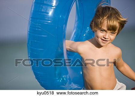 Boy holding an inflatable ring on the beach View Large Photo Image Stock Photo - Boy holding an inflatable ring on the beach. Fotosearch