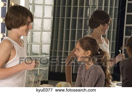 Boy holding toothbrush with his sister smiling in front of him View Large Photo Image Stock Photo - Boy holding toothbrush with his sister smiling in front of him. Fotosearch