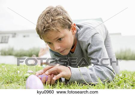 Boy looking at an Easter egg View Large Photo Image Stock Image - Boy looking at an Easter egg. Fotosearch