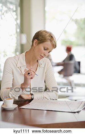 Businesswoman sitting in a restaurant and reading a financial newspaper View Large Photo Image Stock Image - Businesswoman sitting in a restaurant and reading a financial newspaper. Fotosearch