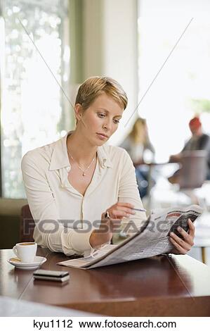 Businesswoman sitting in a restaurant and reading a financial newspaper View Large Photo Image Stock Image - Businesswoman sitting in a restaurant and reading a financial newspaper. Fotosearch