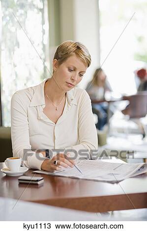 Businesswoman sitting in a restaurant and reading a financial newspaper View Large Photo Image Stock Image - Businesswoman sitting in a restaurant and reading a financial newspaper. Fotosearch