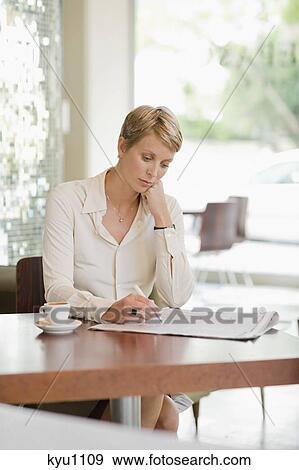 Businesswoman sitting in a restaurant and reading a financial newspaper View Large Photo Image Stock Photo - Businesswoman sitting in a restaurant and reading a financial newspaper. Fotosearch