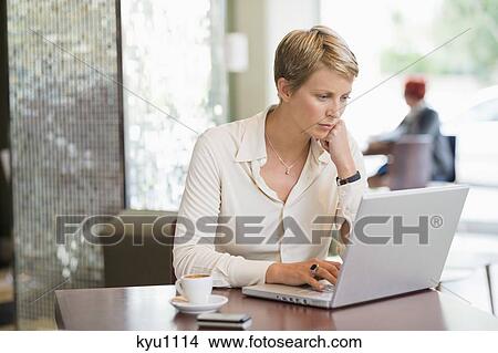 Businesswoman working on a laptop in a restaurant View Large Photo Image Picture - Businesswoman working on a laptop in a restaurant. Fotosearch