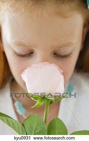 Stock Image - Close-up of a flower girl smelling a flower. Fotosearch