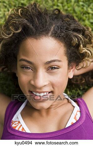 Close-up of a girl lying on the grass and smiling View Large Photo Image Picture - Close-up of a girl lying on the grass and smiling. Fotosearch