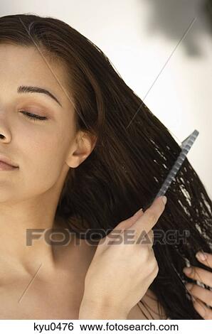 Close-up of a woman combing her hair View Large Photo Image Stock Photograph - Close-up of a woman combing her hair. Fotosearch