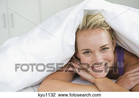Close-up of a woman lying on the bed and smiling View Large Photo Image Stock Image - Close-up of a woman lying on the bed and smiling. Fotosearch