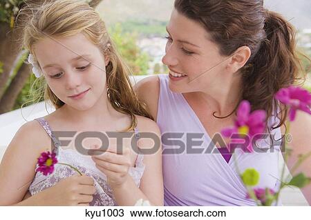 Stock Image - Close-up of a woman smiling with her daughter holding a flower. Fotosearch