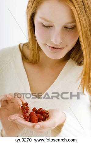 Stock Image - Close-up of a young woman holding berry fruits. Fotosearch