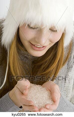 Stock Photography - Close-up of a young woman holding crystal salt in her cupped hands and smiling. Fotosearch