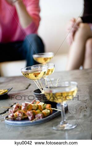 Stock Image - Close-up of glasses of champagne and cocktail snacks. Fotosearch