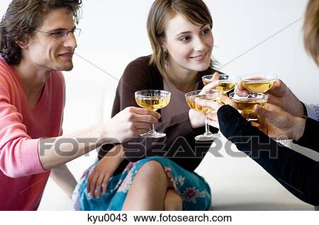 Stock Image - Couple and 3 people clinking glasses of champagne. Fotosearch