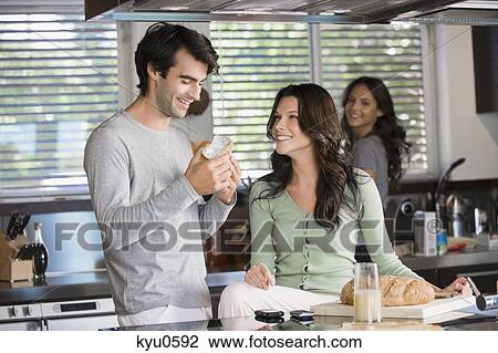 Stock Image - Couple having breakfast in the kitchen. Fotosearch
