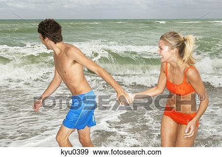 Stock Photo - Couple holding hands and walking on the beach. Fotosearch